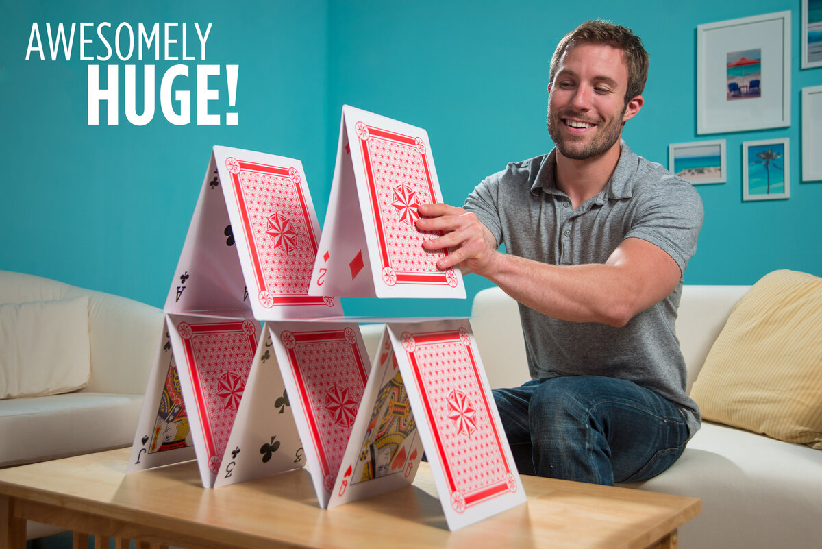 Man builds a house of cards out of his jumbo playing cards.