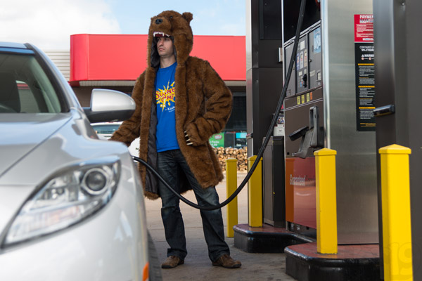 Man pumping gas while wearing the Workaholics Bear Coat.