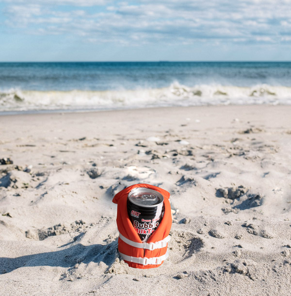 Can of bubble tea on a beach in a Beverage Life Vest