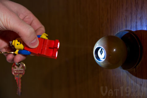 Press the logo button on the LEGO minifigure keychain's torso to illuminate his feet.